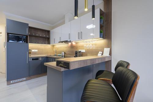 una cocina con armarios azules y una encimera con 2 sillas en Gere ArteVino Apartman, en Villány