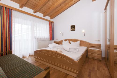 una camera da letto con un letto con lenzuola bianche e una finestra di Appartements Kristall a Nauders