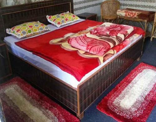 a large wooden bed with a red blanket on it at Devbhoomi by StayApart in Ukhimath