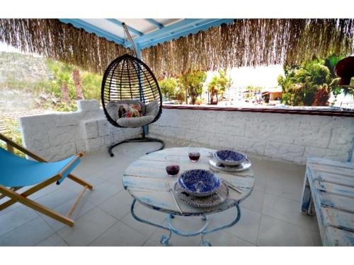 une terrasse avec une table, une chaise et une balançoire dans l'établissement Bozburun Sailor's House, à Marmaris