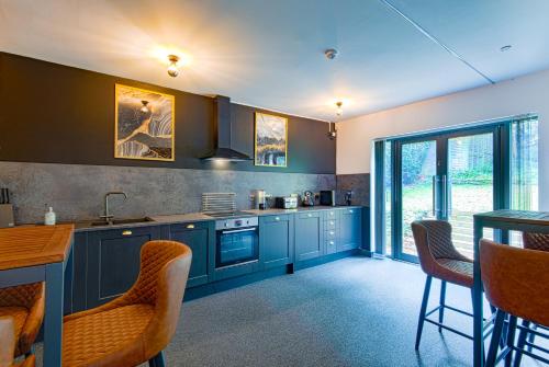 cocina con armarios azules, mesa y sillas en The Headingley House Leeds - Hot Tub - Sleeps Up To 12 - EV Charging, en Leeds