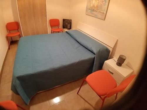 a bedroom with a bed and two orange chairs at casa torre di ligny in Trapani