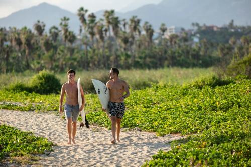 two men walking down a beach with their surfboards at Drift San Jose del Cabo, a Member of Design Hotels in San José del Cabo