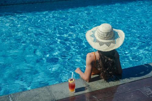 a woman in a hat sitting in a pool with a drink at Holiday Inn Bali Sanur, an IHG Hotel in Sanur