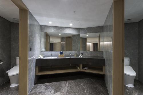 a bathroom with a sink and a toilet and a mirror at Golden Tulip FAB Hotel New Taipei in Tamsui