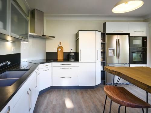 a kitchen with white cabinets and a wooden table at Gîte Des Caves Secrètes in Tiffauges