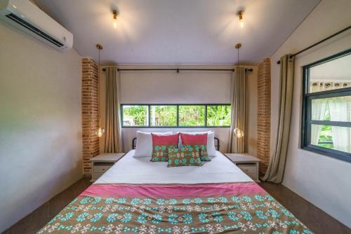 a bedroom with a large bed with two windows at Villa Upeksha - Huge 1-bedroom Villa with pool in Pererenan in Munggu