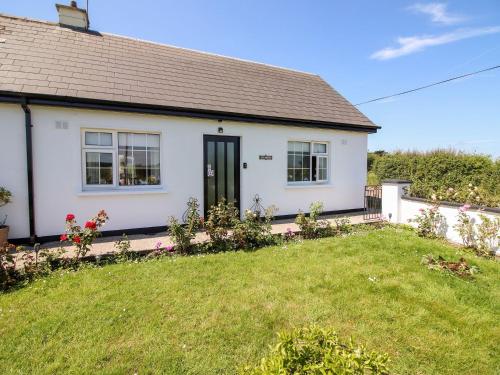 a white house with a green lawn in front of it at Pet friendly Immaculate 2-Bed Cottage in Listowel in Listowel