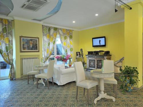 a living room with yellow walls and tables and a fireplace at Hotel Miramare in Maiori