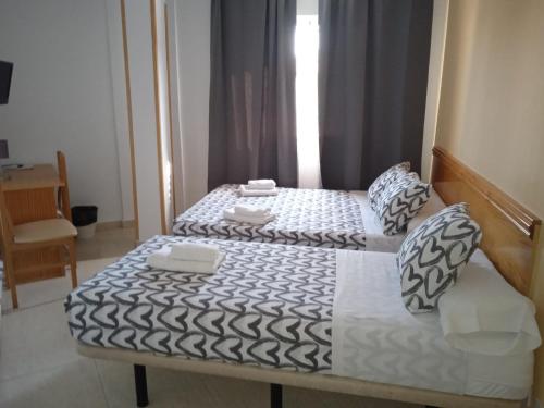 a bedroom with two beds with white and black sheets at HOTEL El ALAMO MADRID in El Álamo