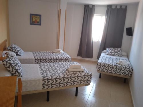 a small room with two beds and a chair at HOTEL El ALAMO MADRID in El Álamo