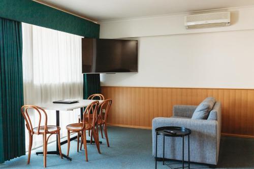 a room with a table and chairs and a tv at Echuca Nirebo Motel in Echuca