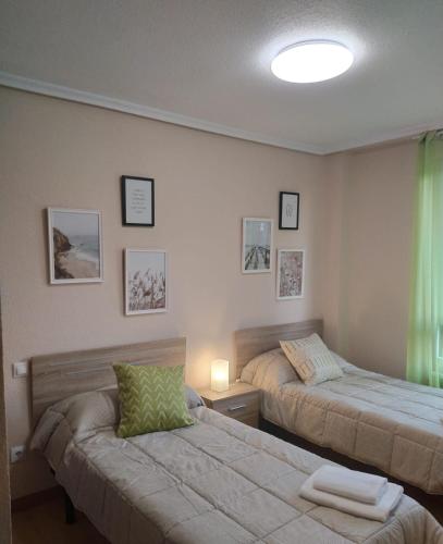 a bedroom with two beds and a lamp and a window at Fantástico apartamento en las playas de Suances in Suances