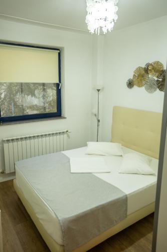 a bedroom with a white bed and a chandelier at Iassium Residence Iasi in Iaşi