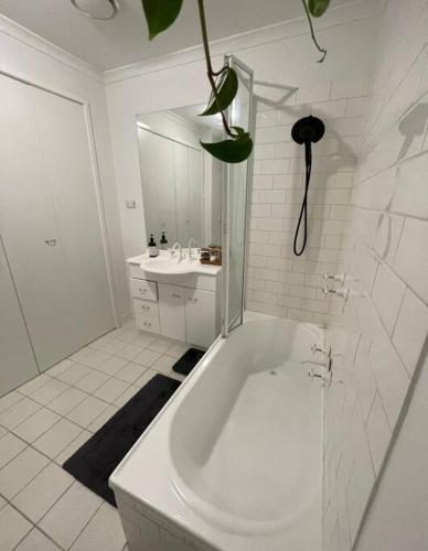 a white bathroom with a tub and a sink at South Melbourne Central 1BR - 106 in Melbourne