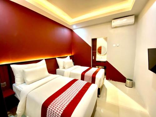 two beds in a hotel room with red walls at Petro Inn Takengon in Takengon