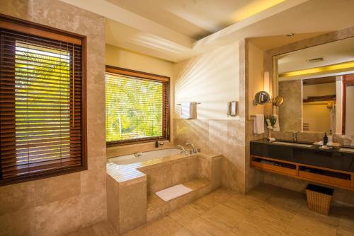 a bathroom with a tub and a sink and a mirror at Shanti Maurice Resort & Spa in Bel Ombre