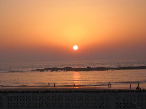people walking on the beach at sunset at Le Calme a Temara in Temara