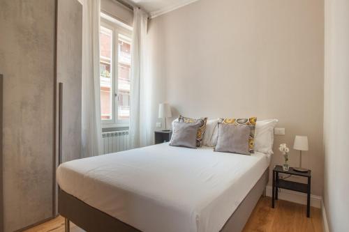 een wit bed in een witte slaapkamer met een raam bij Italian Experience-Lungarno Suite Apartment in Florence