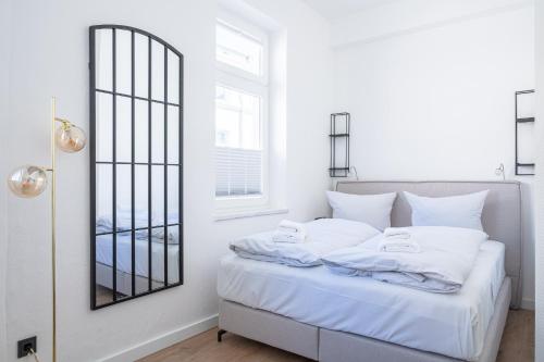 um quarto branco com uma cama com um espelho em JOHOUSE Apartment 08 em Warnemünde