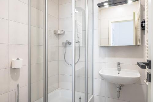uma casa de banho branca com um chuveiro e um lavatório. em JOHOUSE Apartment 08 em Warnemünde