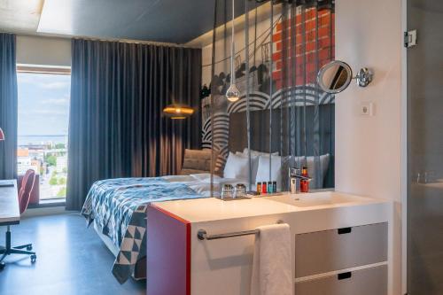 a bedroom with a bed and a sink and a mirror at Solo Sokos Hotel Torni Tampere in Tampere
