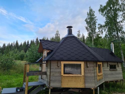 a log cabin with a black roof and a window at House with private beach in Rautalampi