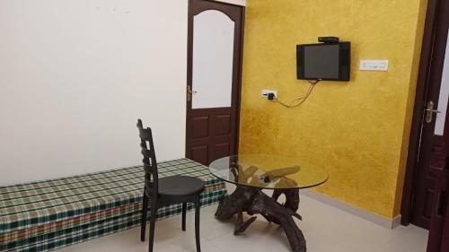 a glass table with a chair and a tv on a wall at COCHIN HOMES in Ernakulam