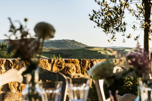 a table with chairs and wine glasses in front of a wall at Agriturismo Poggio Il Castellare in Montalcino