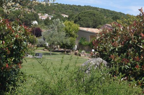 um jardim com uma casa ao fundo em Les Jardins De Santa Giulia - Charmante chambre d'hôte em Porto-Vecchio