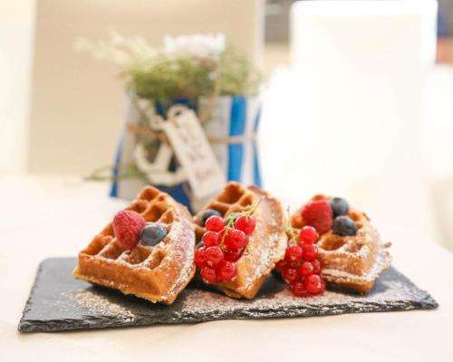 a plate with three waffles with berries on it at Hotel Polo in Rimini