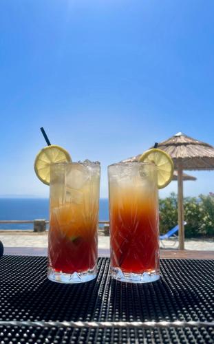 two cocktails sitting on a table near the ocean at Charakas Horizon in Gavrion