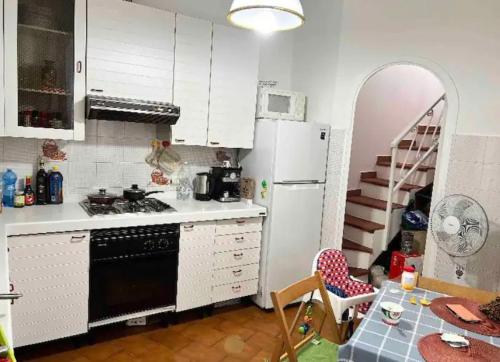 een keuken met een zwarte en witte koelkast en een tafel bij Cheerful Room, Sharing kitchen in a Cosy Family Art House, Ideal for one person or couple in Sanremo