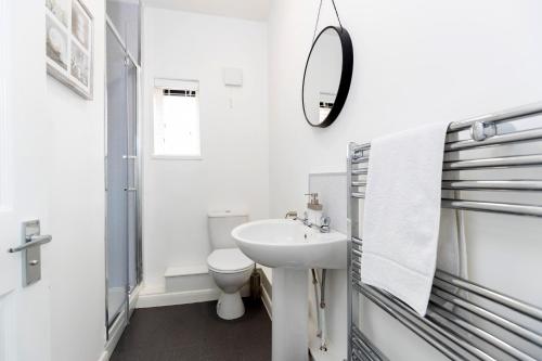 a white bathroom with a sink and a mirror at Amazing House with Central Location in Darlington