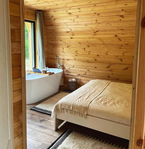 a bedroom with a wooden wall and a tub and a bed at Hygge Cabana in Malaia