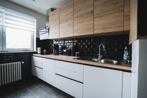 cocina con armarios blancos, fregadero y ventana en La Villa Delsa, en Namur