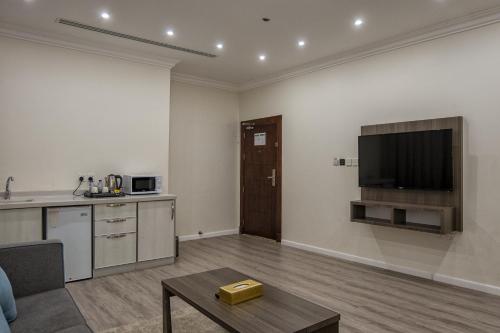 a living room with a kitchen and a tv on the wall at فندق كارم in Raḩīmah