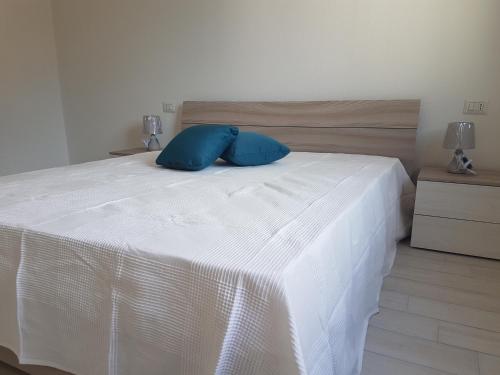 a white bed with two blue pillows on it at CASE ORCHIDEA - ROSA BLU in La Caletta
