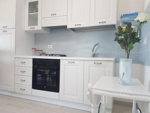 a kitchen with white cabinets and a vase of flowers on a table at CASE ORCHIDEA - ROSA BLU in La Caletta