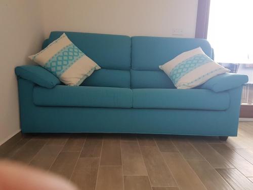 a blue couch with two pillows on it in a living room at CASE ORCHIDEA - ROSA BLU in La Caletta