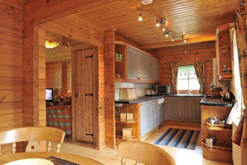 una cocina en una cabaña de madera con mesa y sillas en Ardlui Lochside Lodges, en Ardlui