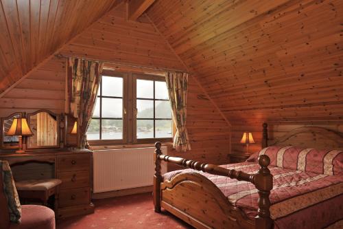 1 dormitorio con 1 cama en una cabaña de madera en Ardlui Lochside Lodges, en Ardlui