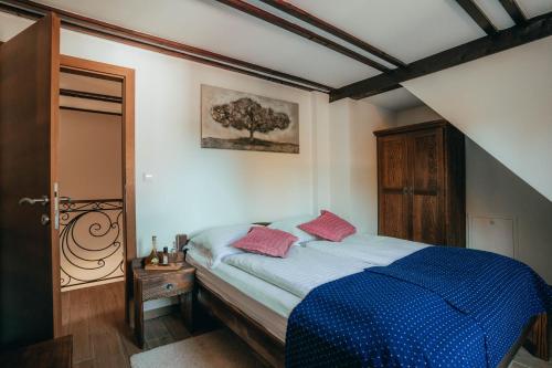 a bedroom with a bed with blue sheets and pink pillows at Green Garden Plitvice lakes in Plitvica selo