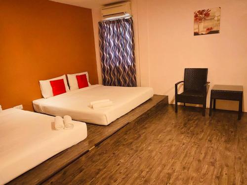 a room with two beds and a table and a chair at Orange Hotel Segamat in Segamat