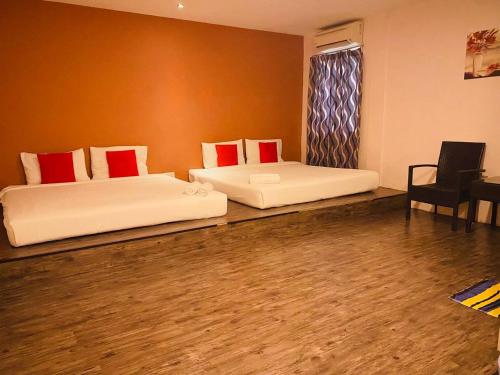 two beds in a room with a chair and a table at Orange Hotel Segamat in Segamat