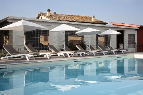 a group of chairs and umbrellas next to a pool at Agriturismo le Capannacce Urbania in Urbania