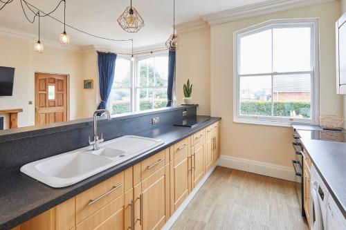 a large kitchen with a sink and two windows at Ground Floor at the Old Vicarage in Scarborough