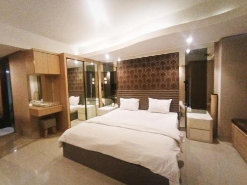 a bedroom with a large white bed and a bathroom at Cozy The H Residence Cawang by Bonzela Property in Jakarta