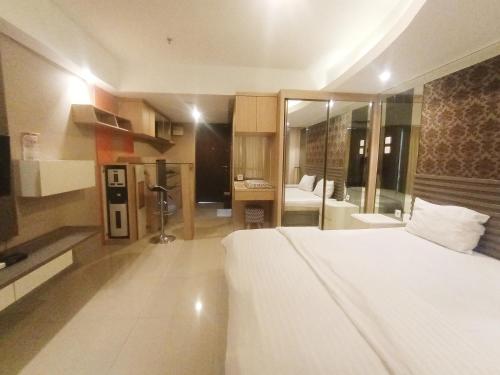 a bedroom with a large white bed and a bathroom at Cozy The H Residence Cawang by Bonzela Property in Jakarta