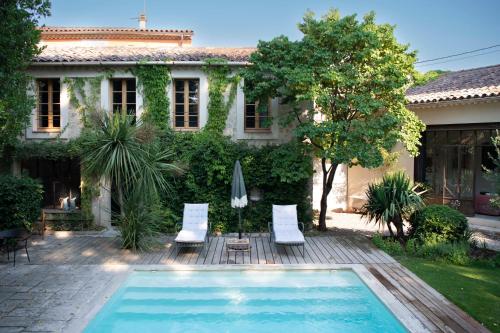 una piscina di fronte a una casa con due sedie da giardino e un ombrellone di Maison Sumiane a Brignoles